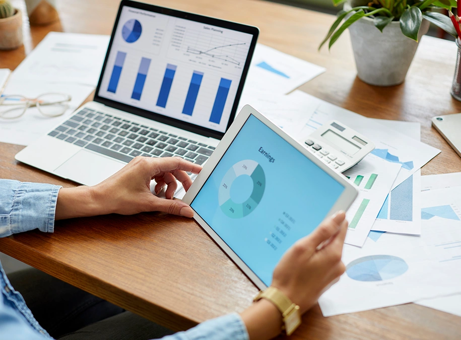 Person analyzing charts on tablet and laptop.